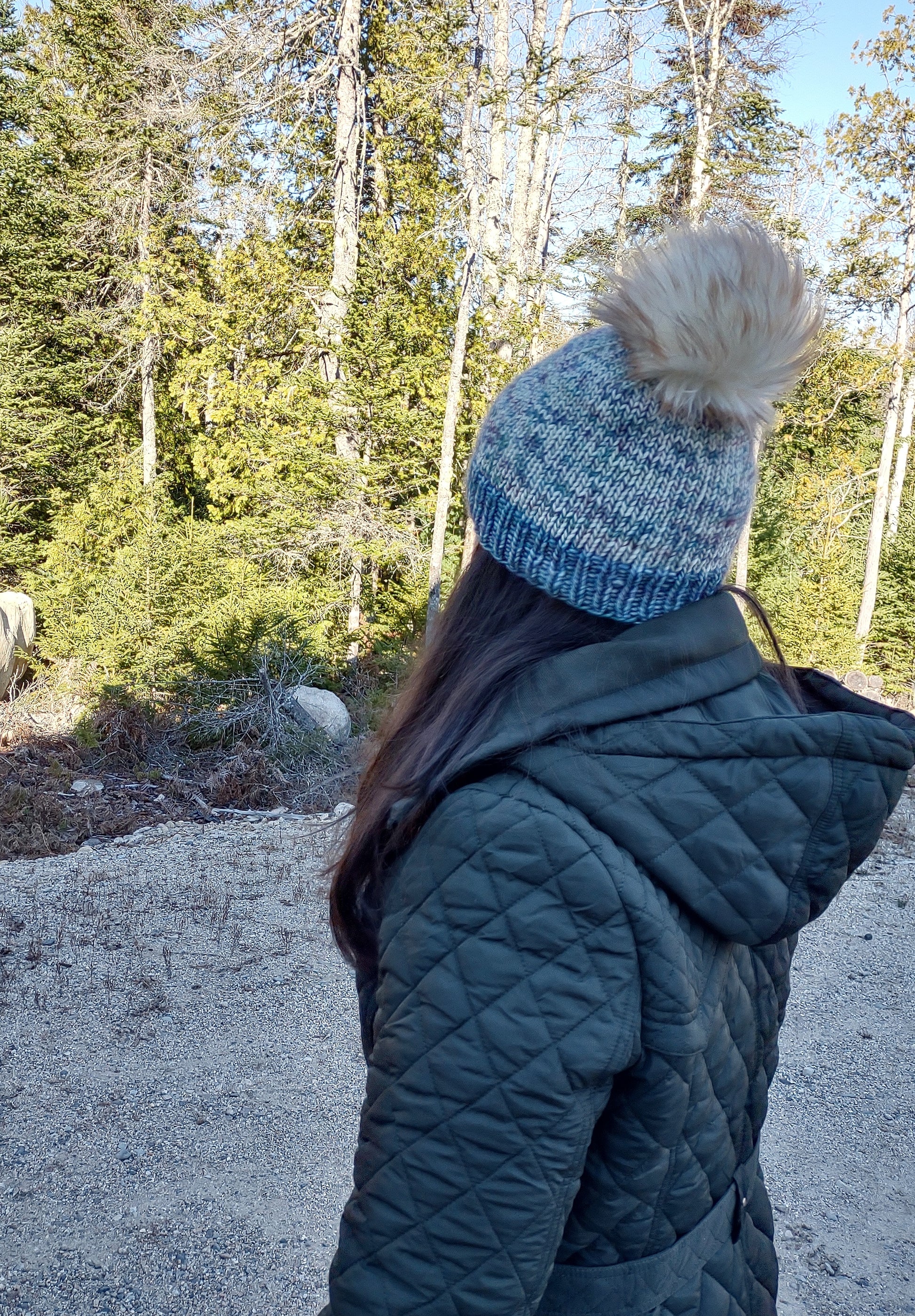 Woman wearing hat with fluffy faux fur pom pom